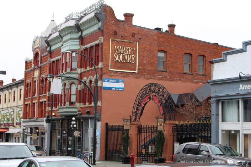 Metal archway beside red brick building announcing entry to Trounce Alley