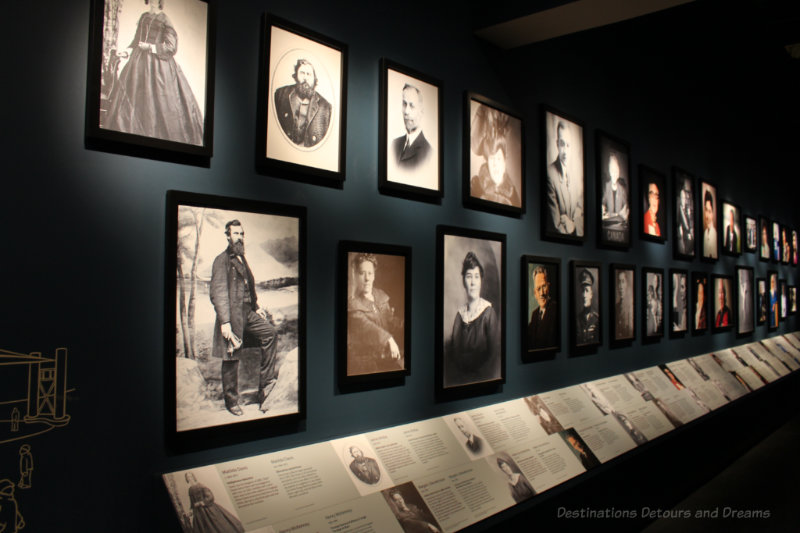 A wall of photos with information on a shelf below about 30 prominent people in Winnipeg's history