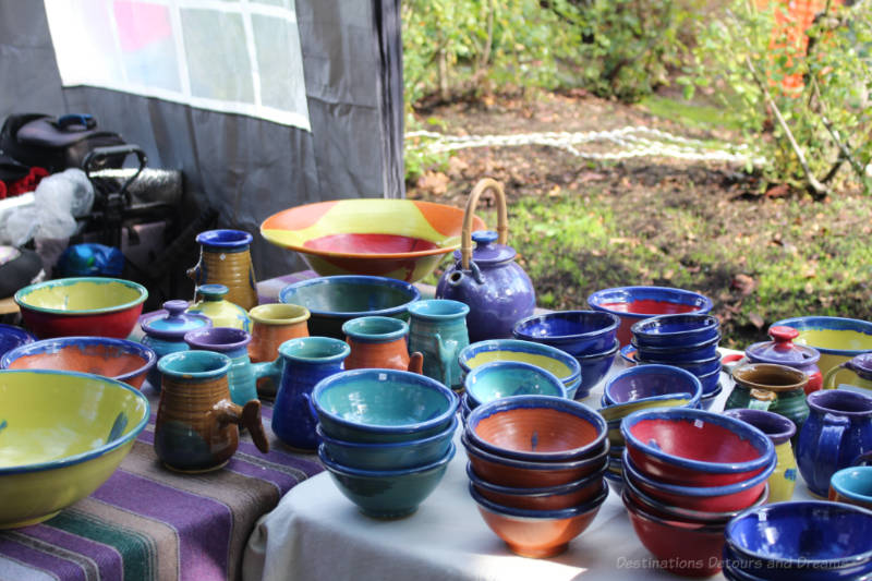 Table containing bright blue, red, and yellow pottery at Salt Spring Island Saturday Market