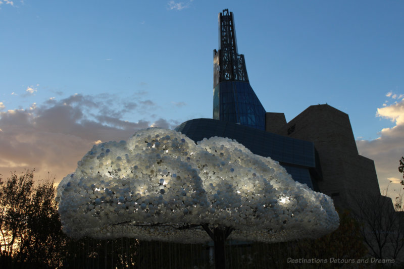 An interactive light art installation looking like a cloud with the Canadian Museum for Human Rights in the background