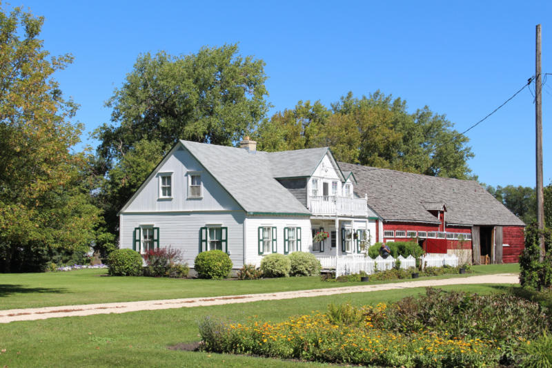 White wooden house and attached red barn in a Manitoba Mennonite street village