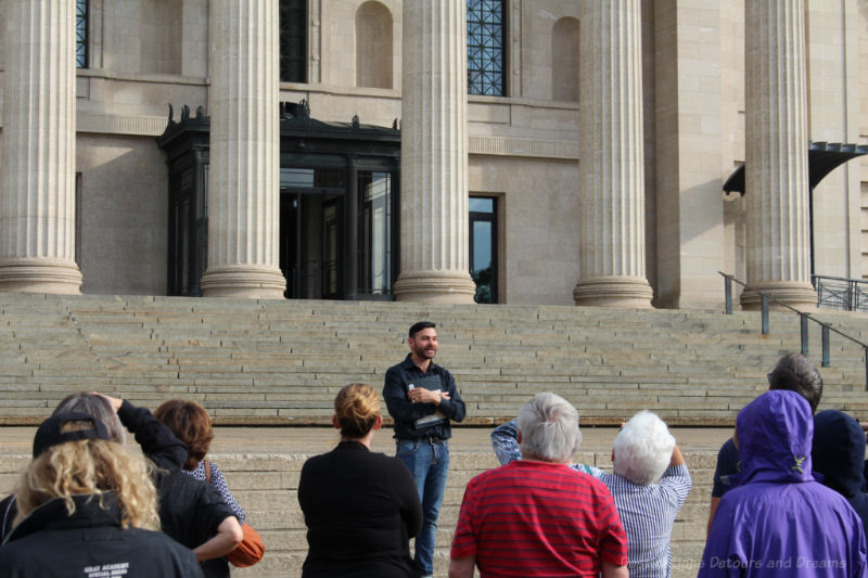 Tour guide talking to group at the bottom of the Tyndall stone steps leading into the Manitoba Legislative Building
