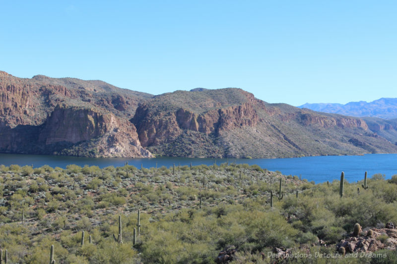 Road Trip Tips: Apache Trail Scenic Stop View of blue lake surrounded by cacti-covered mountains