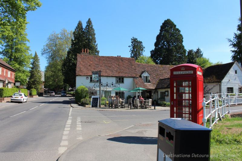 A crossroads in an English village with a red telephone booth and old mill turned restuarant