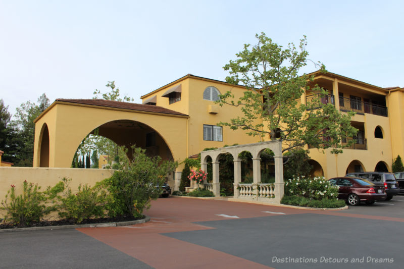 A Mediterranean-themed two-story hotel with yellowish stucco finish and covered drive-up