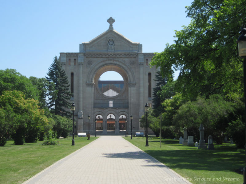 Stone cathedral facade at the back of large lawn and cemetery