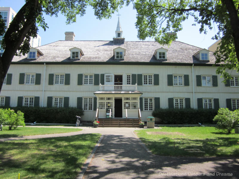 White oak log building with green trim housing St. Boniface Museum