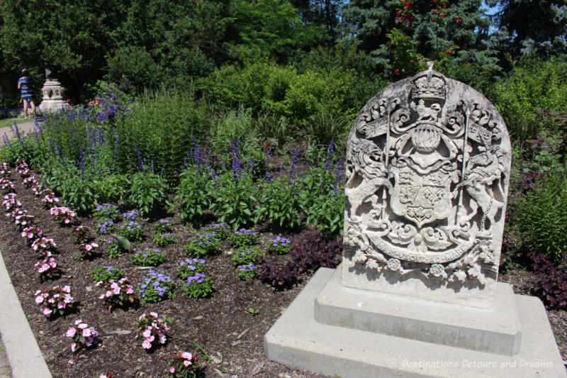 Stone coat of arms sculpture in a flower bed