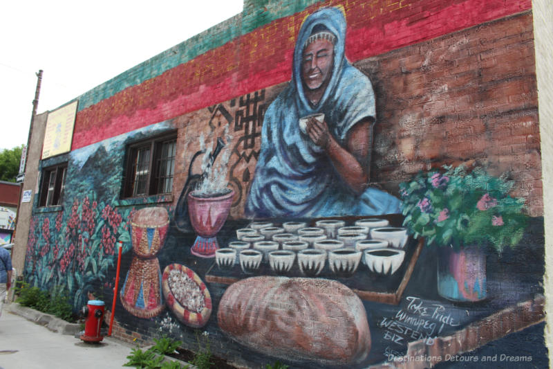 Mural showing Ethiopian women in front of tray of coffee cups with coffee brewing and coffee plants to her right