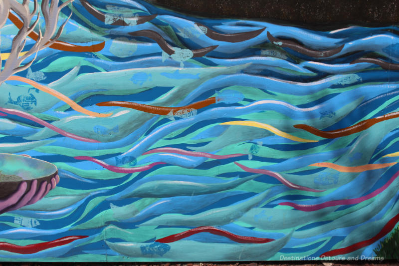Wavy lines of blue and green with hints of yellow and red represent waters in a mural