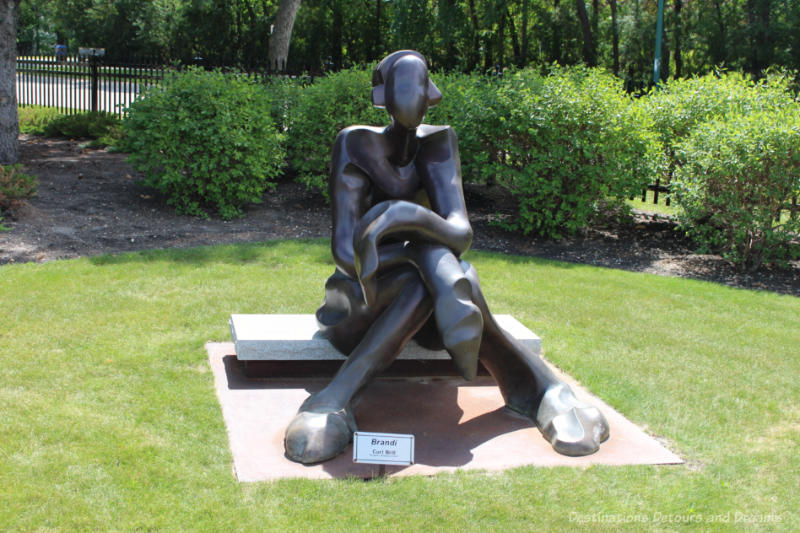 A sculpture of a stylized seated female figure on the grounds of a park