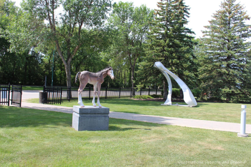 A sculpture of a horse and another of a stylized metal shape in a park in Altona, Manitoba