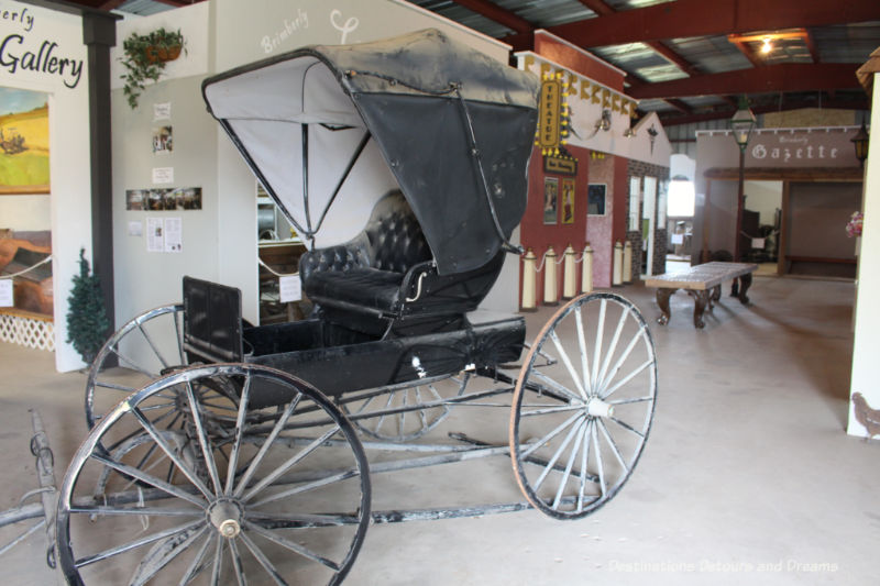 A carriage meant to be drawn by horses in the hallway of a museum created like a street village