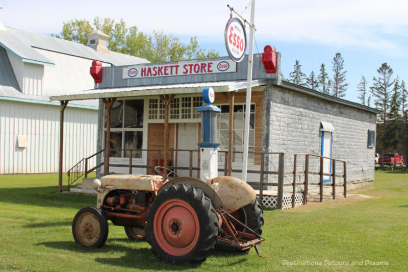 Rusted tractor in front of an old one-story store with an old Esso gas pump