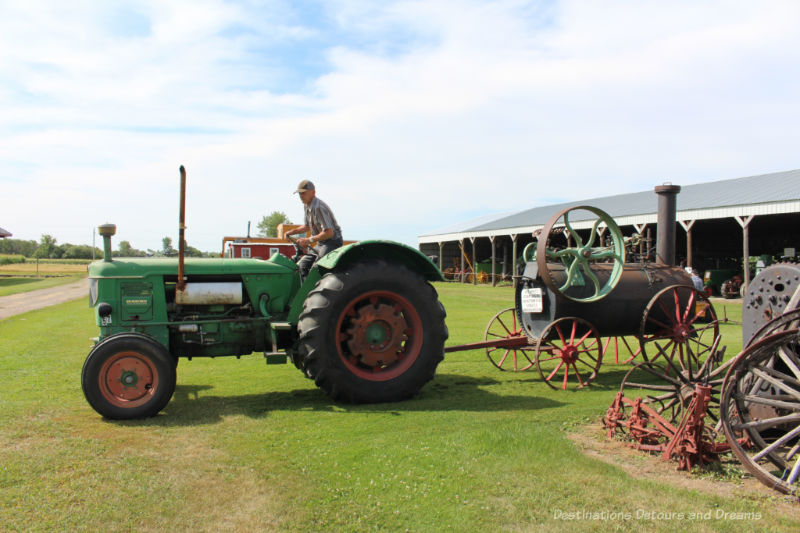 Man on a vintage tractor pulling a steam engine