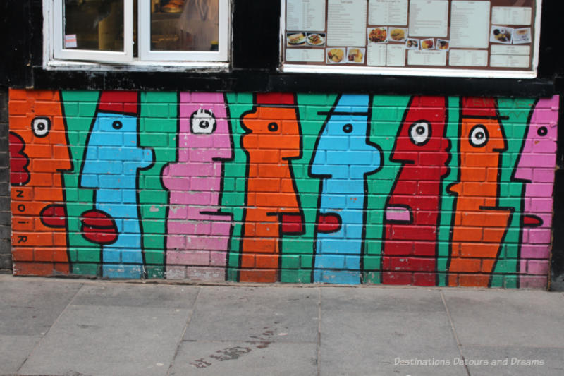 London street art in Shoreditch: Stylized long skinny faces in orange, red, blue, and pink - streetart by noir