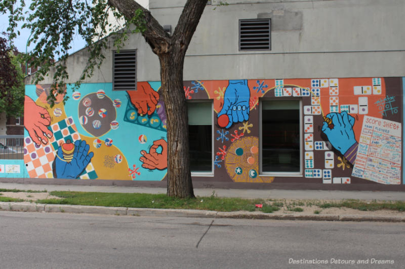 A mural showing hands playing different games - dice, marbles, board games