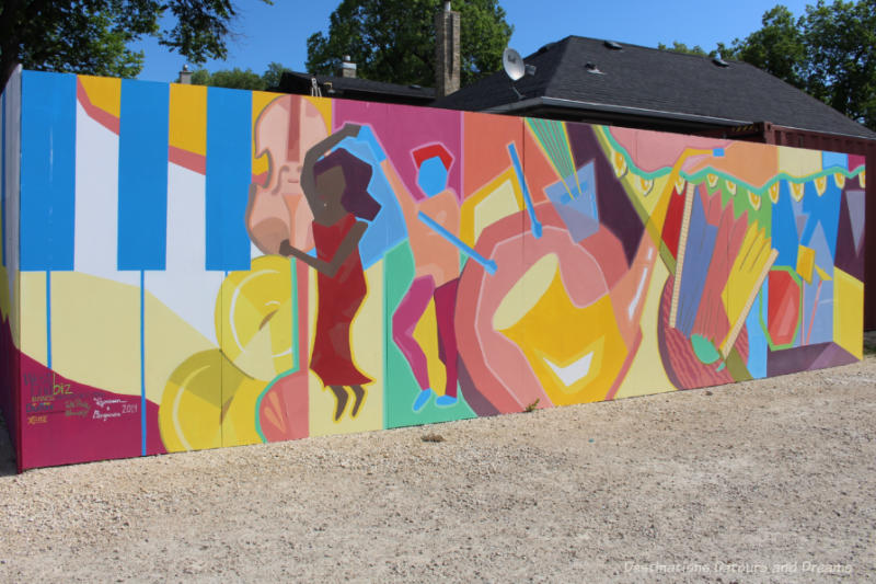 Mural on a board at the edge of a parking lot featured geometric designs in many colours representing musical instruments from various countrie