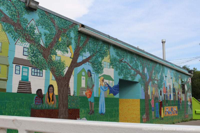 Mural on the side of a building showing people of different cultures growing and preparing food.