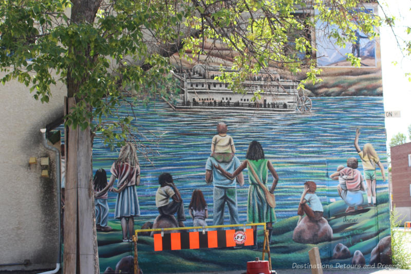 Mural showing adults and children looking out to sea at a steam ship and waving