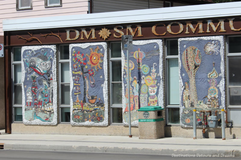 Four mosaic panels on a building front, each with curved white edging and blue background and showing different scenes