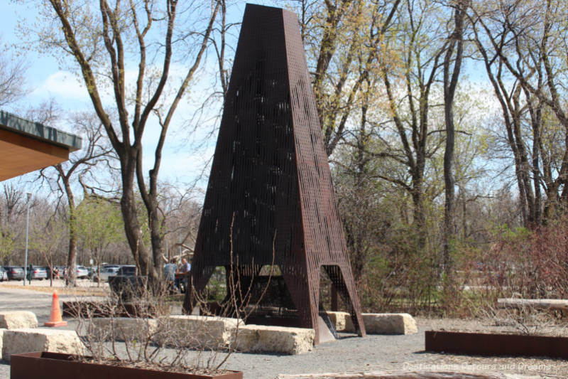 A tall steel working fire pit piece of public art in a Winnipeg park