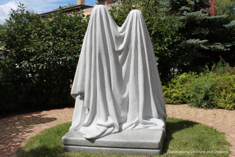 A Winnipeg public art piece featuring two stone figures draped in what looks like a white cloth