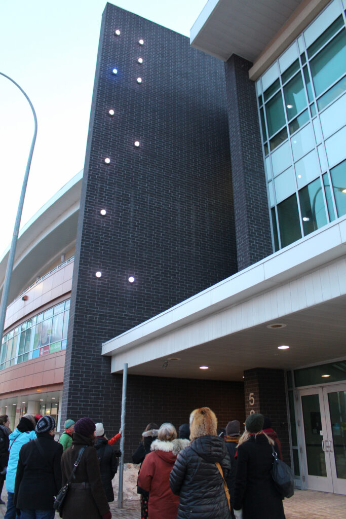 An interactive public art piece in Winnipeg, Manitoba with a pole for handprints which trigger musical notes and lights on the wall