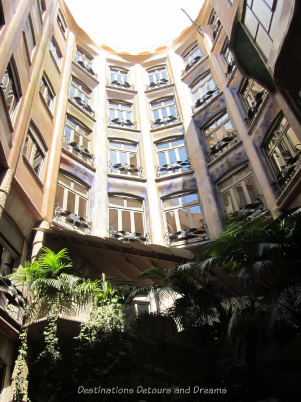 Looking up at the windows and ironwork balcony railings of Casa Milà apartments from the courtyard