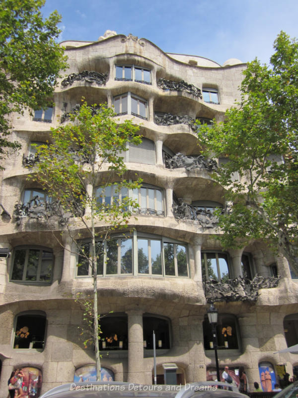 The rough-hewn stone wavy facade and wrought-iron balconies of Casa Milà in Barcelona