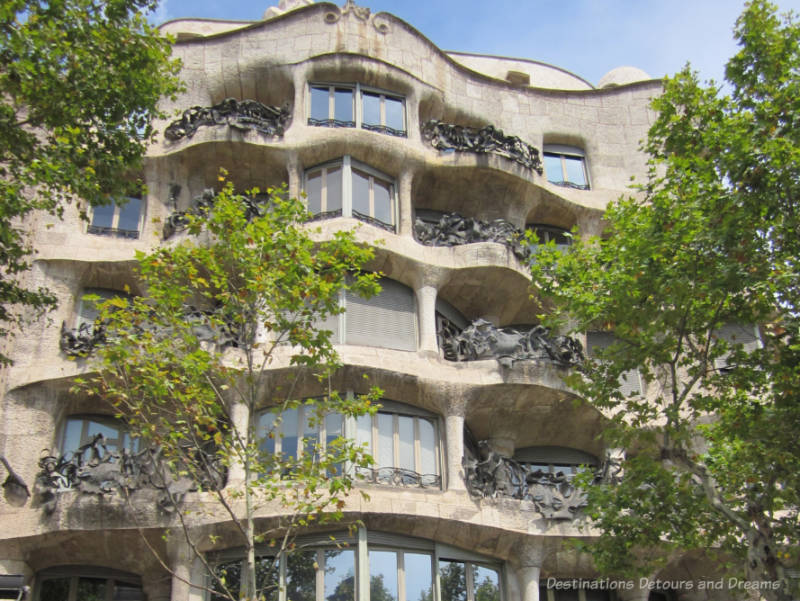 The rough-hewn stone wavy facade and wrought-iron balconies of Casa Milà in Barcelona