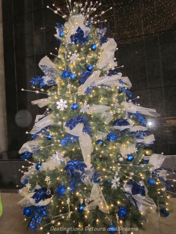 Christmas tree decorated with sheer white bows, sparkly white snowflakes, blue balls, and blue garlands