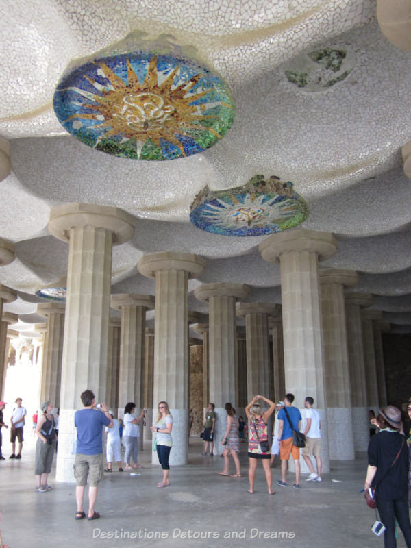 A patio-style area with large columns holding up an undulating ceiling decorated with mosaic disks