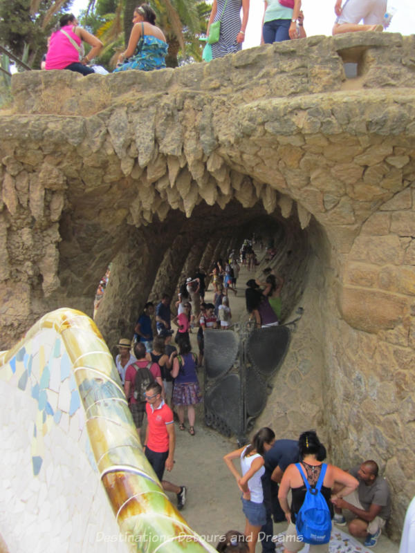 Rough-hewn stone covered pedestrian walkway supporting roadway above