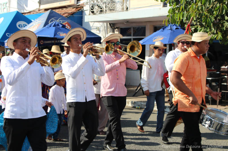 A band of men dressed in traditional Panamanian attire marching and playing in the Thousand Polleras Parade