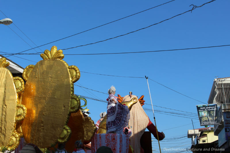 Man using a long pole to life the electrical wires crossing the main street of Las Tablas, Panama so that a parade float could pass through