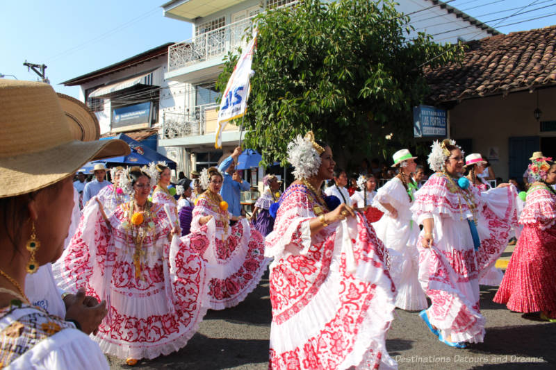 Several women clad in white and red polleras dance through the street in the Thousand Polleras Parade