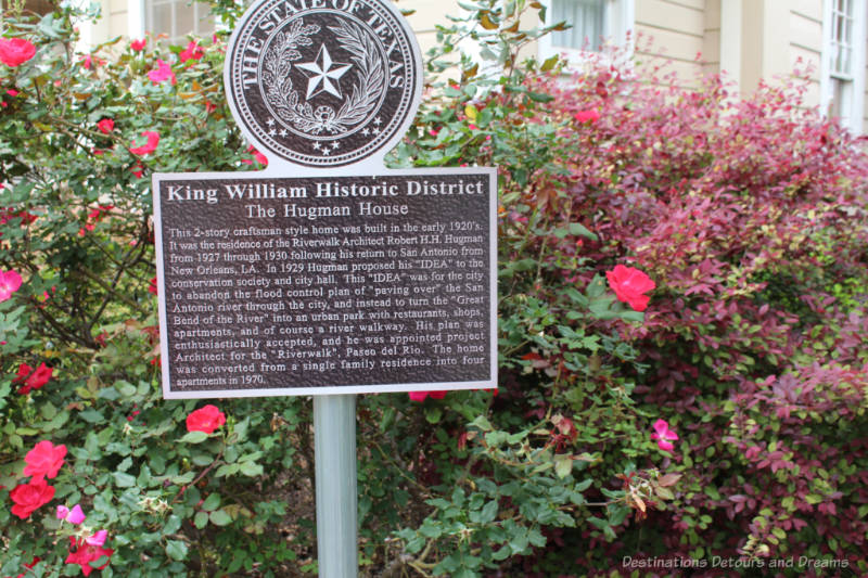 History signage amid flowery shrubs in King William Heritage District in San Antonio