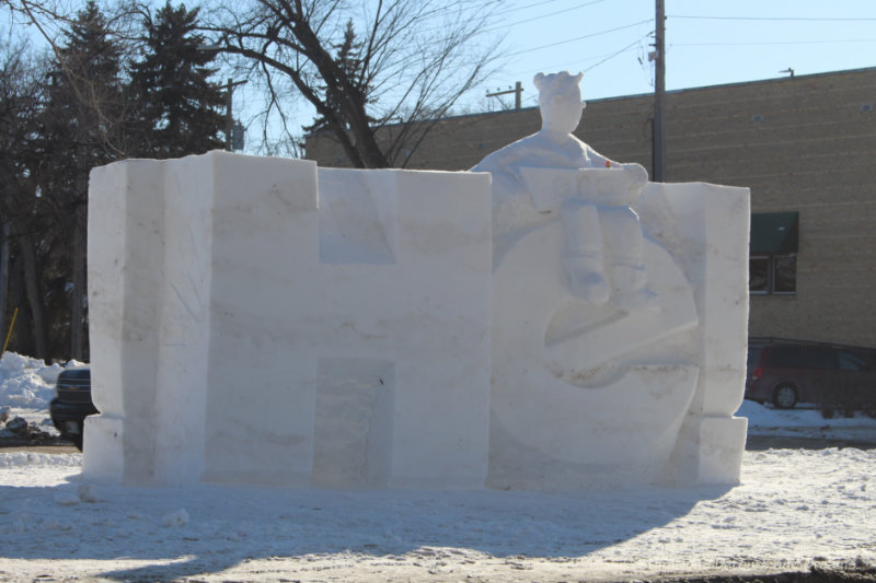 Snow sculpture of figure sitting atop the e in the letter He (part of he ho, Festival du Voyageur