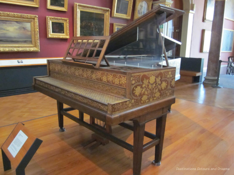 19th century grand piano with gold-coloured flower design covering the wood