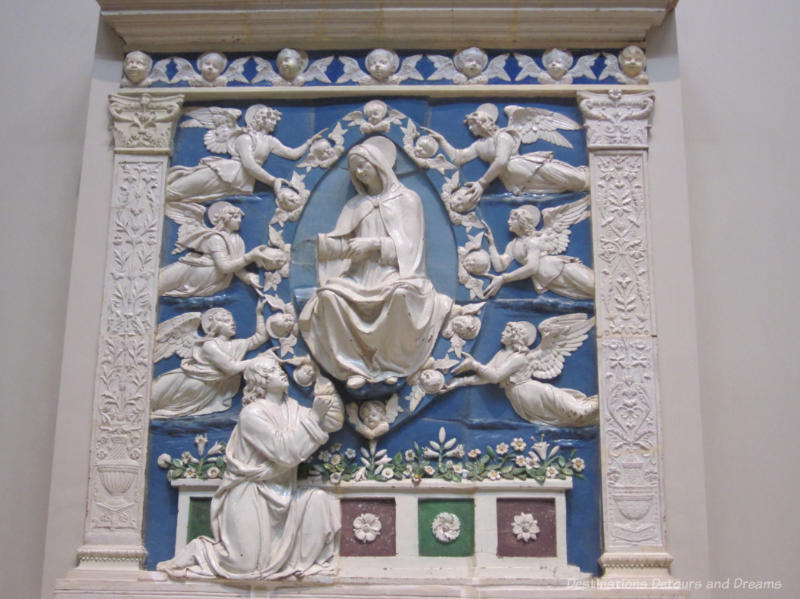 Tin-glazed terracota artwork with blue background and white angelic figures around a central white Madonna