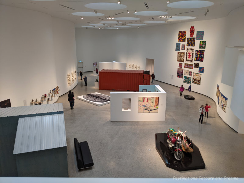 Large sky-lit  two-story white-walled gallery displaying Inuit art of the INUA exhibition, inaugural exhibition of Qaumajuq