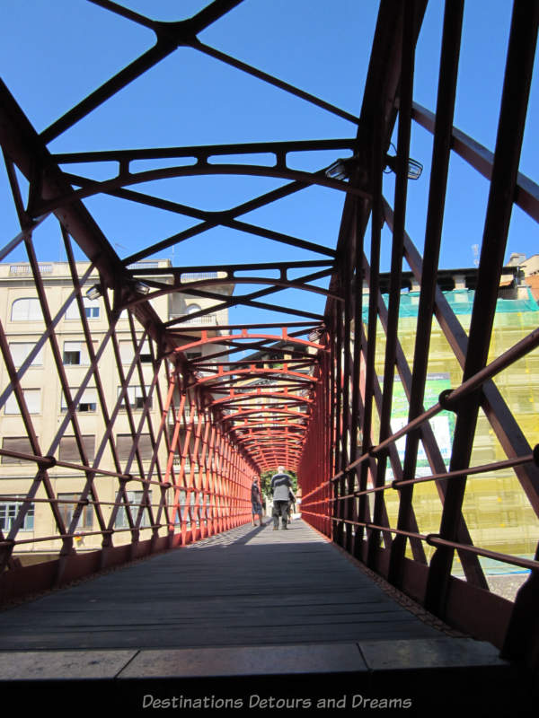 On the Eiffel Bridge in Girona, Spain, with crisscrossing bars forming side walls and a ceiling