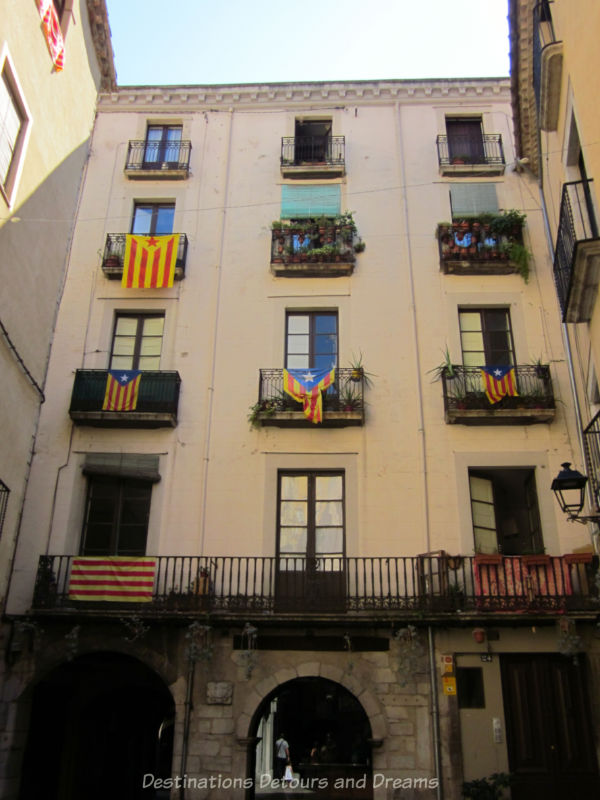 multi-story building with Catalonian flags draped over balcony iron railings