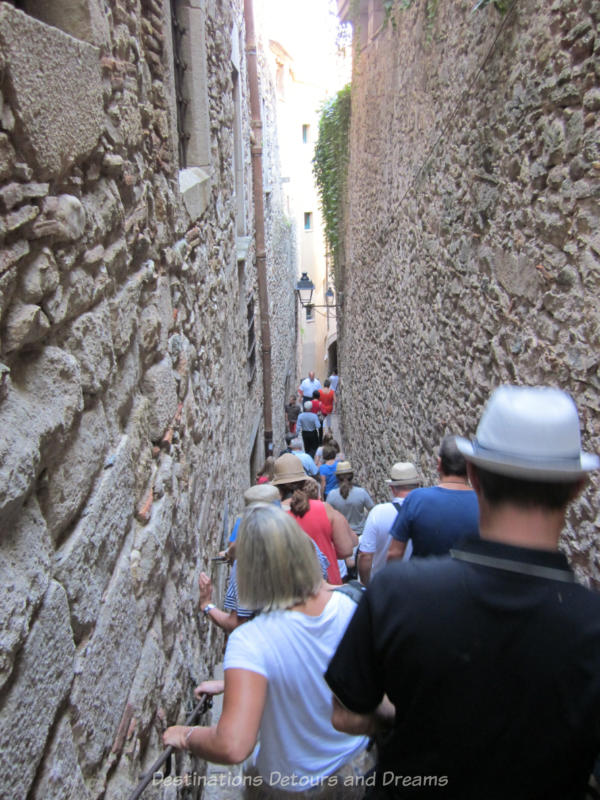 People walking down a steep narrow stone-walled stairway in Girona's old Jewish Quarter