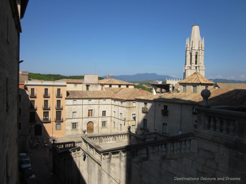 A view overlooking medieval stone buildings of Girona, Spain with hills in the background