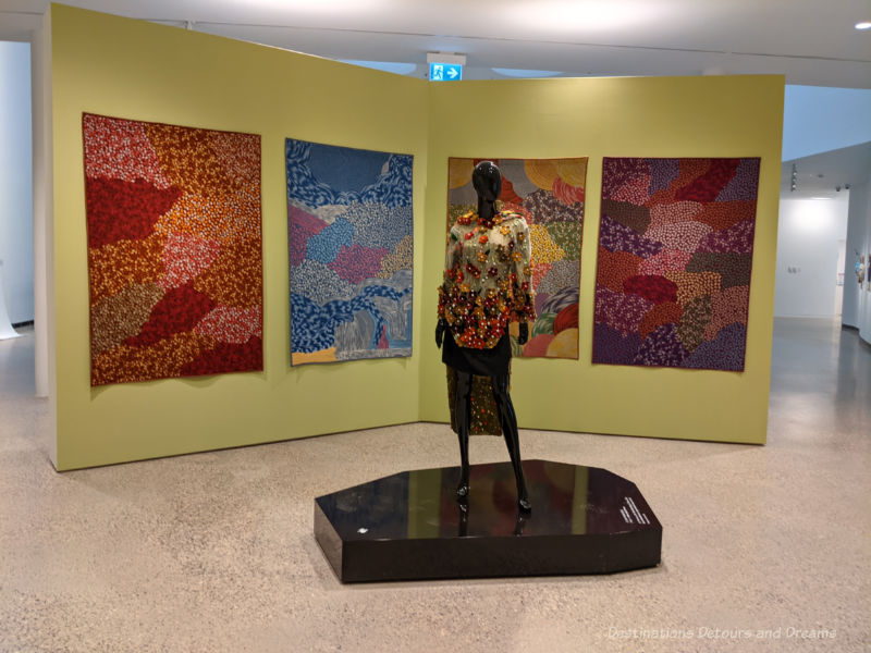 Qaumajug INUA Exhibition Colourful embroidered Inuit wall hangings depicting the four seasons and a mannequin wearing an embroidered top with beads and pearls at an art exhibition at Qaumajuq