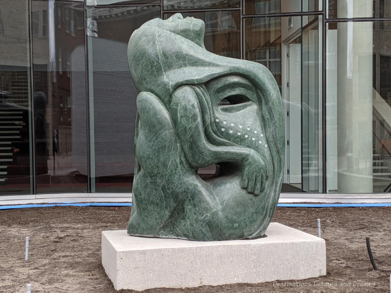 Qaumajuq The Gift Green marble sculpture by Inuit artists Goota Ashoona is a sytlized version of Sedna, the Inuit sea spirit, and the tattooed face of a lady.