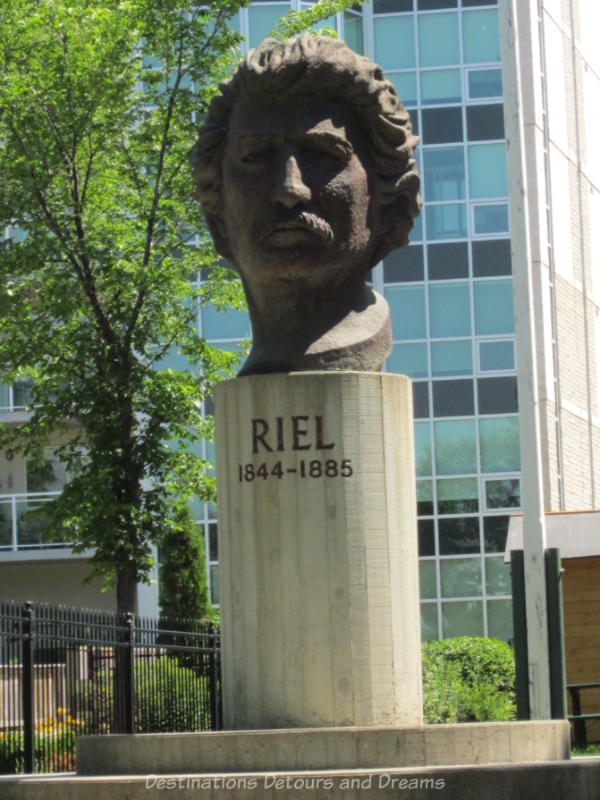 Large statue of the head of Louis Riel resting on a circular stand