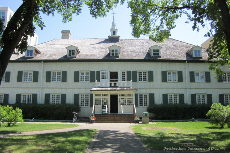 Two-story oak log building painted white with green window shutters. The former convent now houses the St. Boniface Museum in Winnipeg, Manitoba.